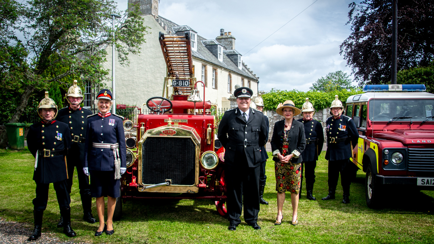 Heritage trust volunteers wearing regalia firefighting uniform, the Lord Lieutenant of Ross and Cromarty wearing full uniform, a 1915 Dennis fire appliance, the Chief Officer of the Scottish Fire and Rescue Service wearing dress uniform, Diana Hamilton-Jones a descendant of James Braidwood and a Scottish Fire and Rescue Service branded Land Rover Discovery