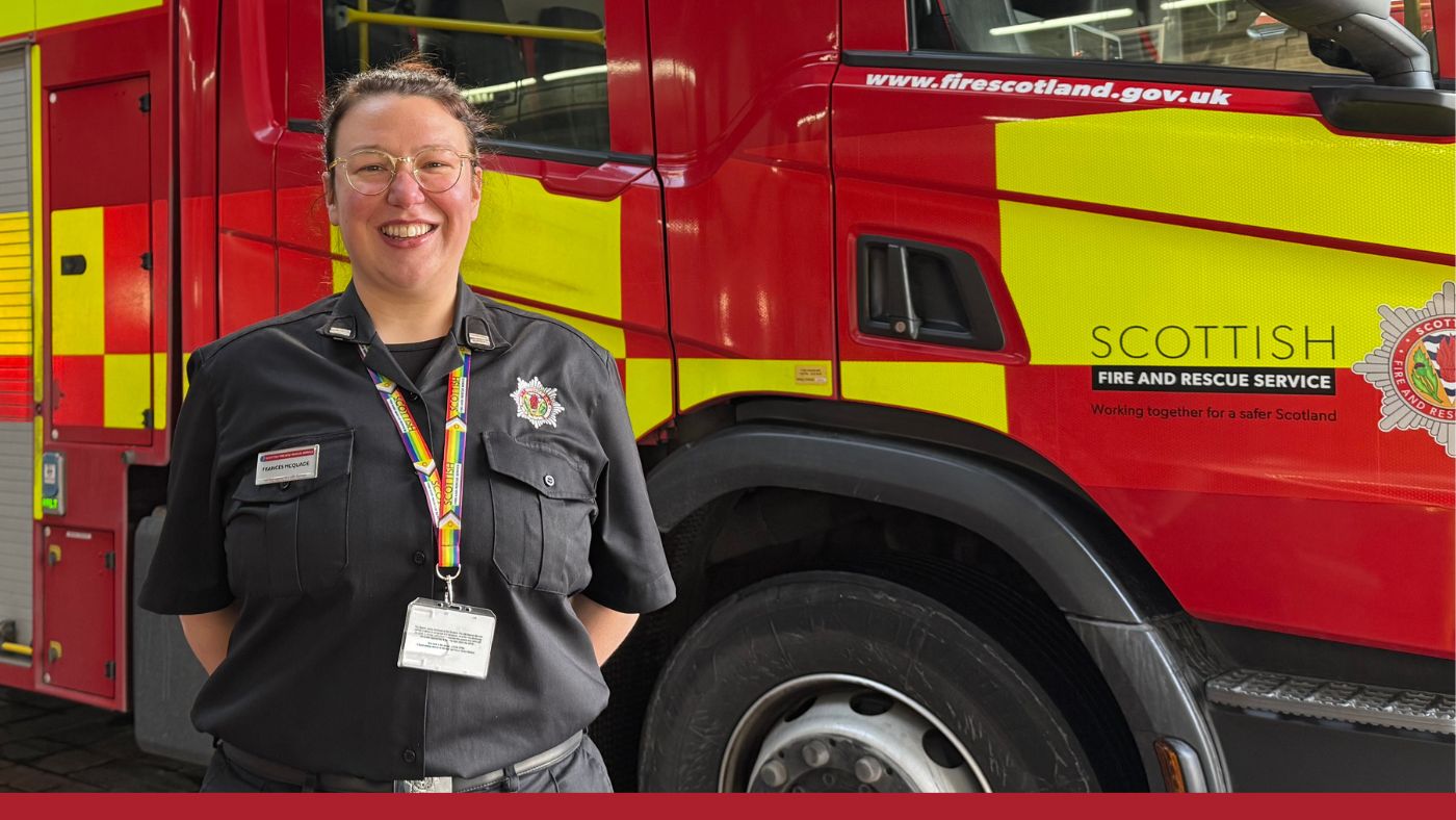 A firefighter is standing beside a red and yellow fire appliance.