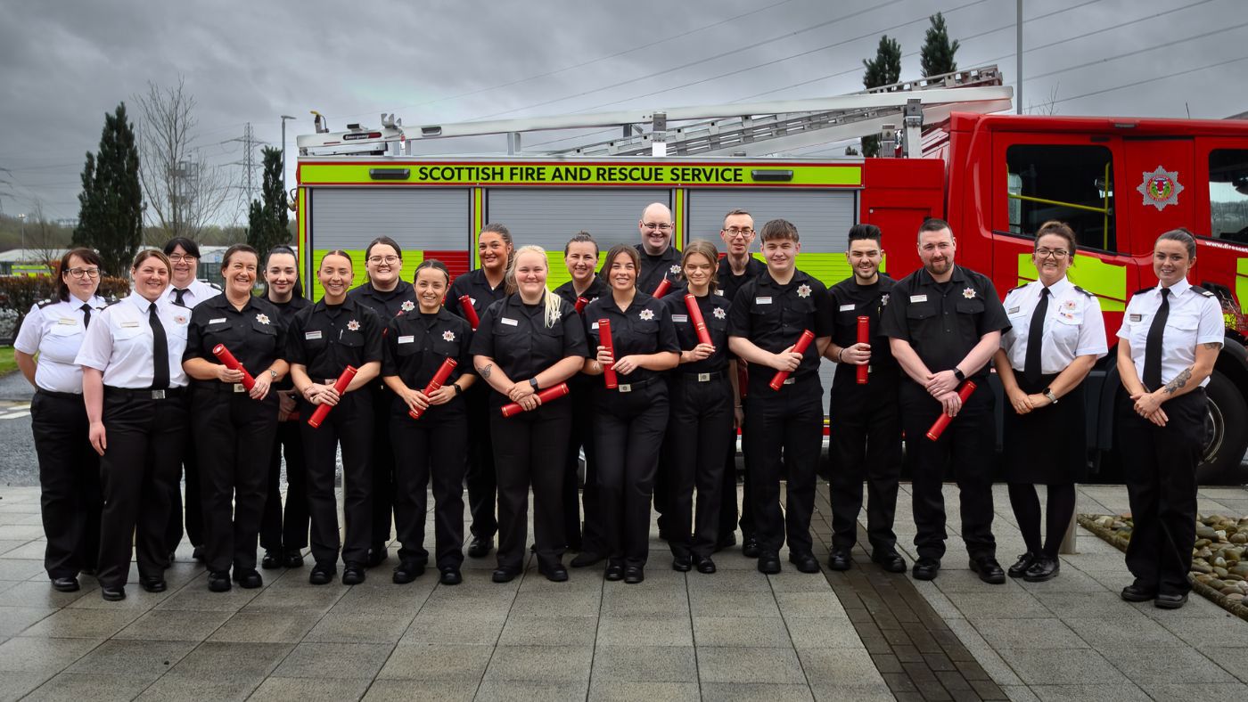 Firefighter Control in black uniform standing in front of a fire appliance