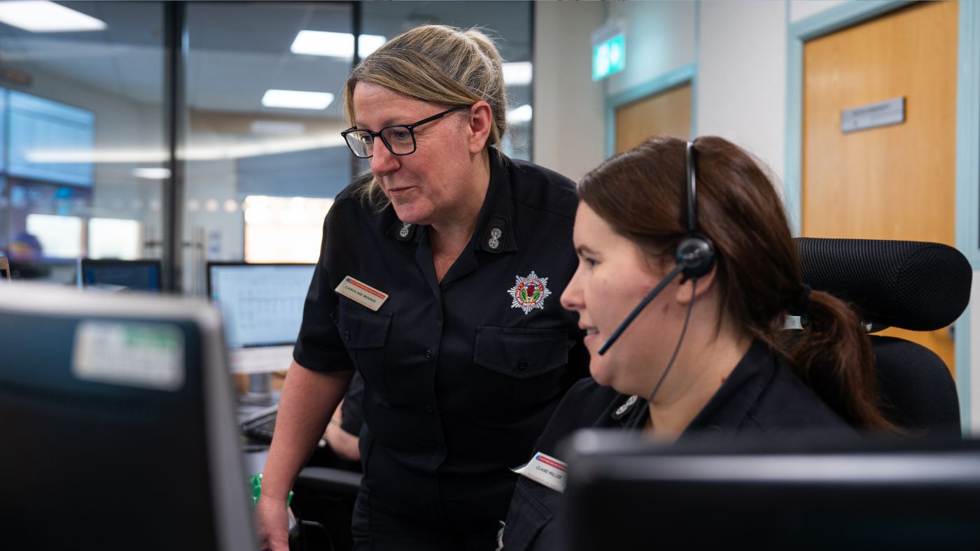 two people wearing black uniforms looking at a computer screen