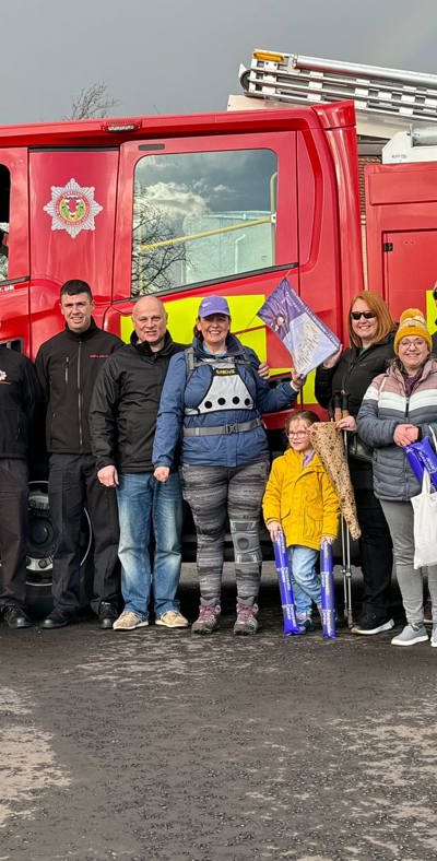 woman stands with friends and family against a fire engine