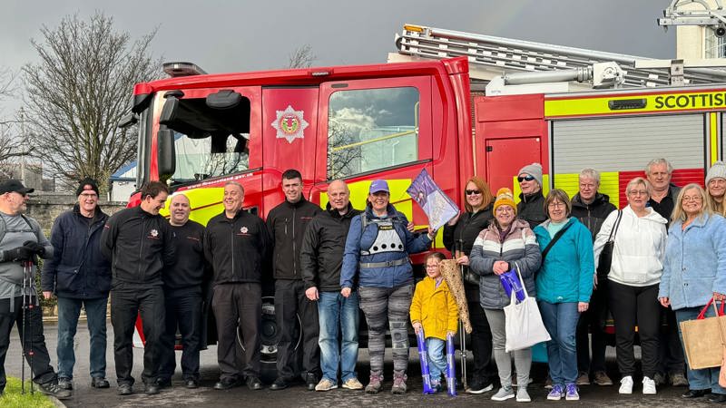 woman stands with friends and family against a fire engine