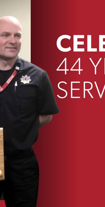 Firefighter Brian Haddow holding an axe mounted on a wooden plaque