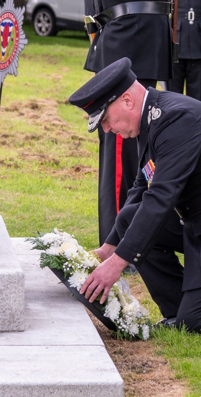 firefighter placing a wreath on a gravestone