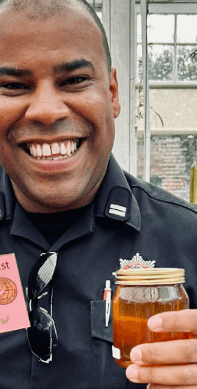 Firefighter smiling with a pot of honey in hand